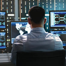 KVM Soultions man sitting at wall of computer monitors